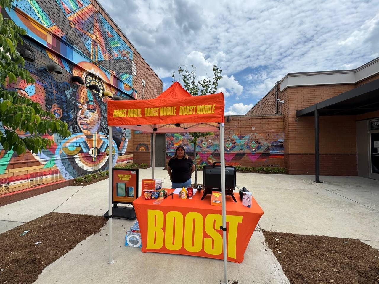 The Boost Mobile tent set up beside a community mural